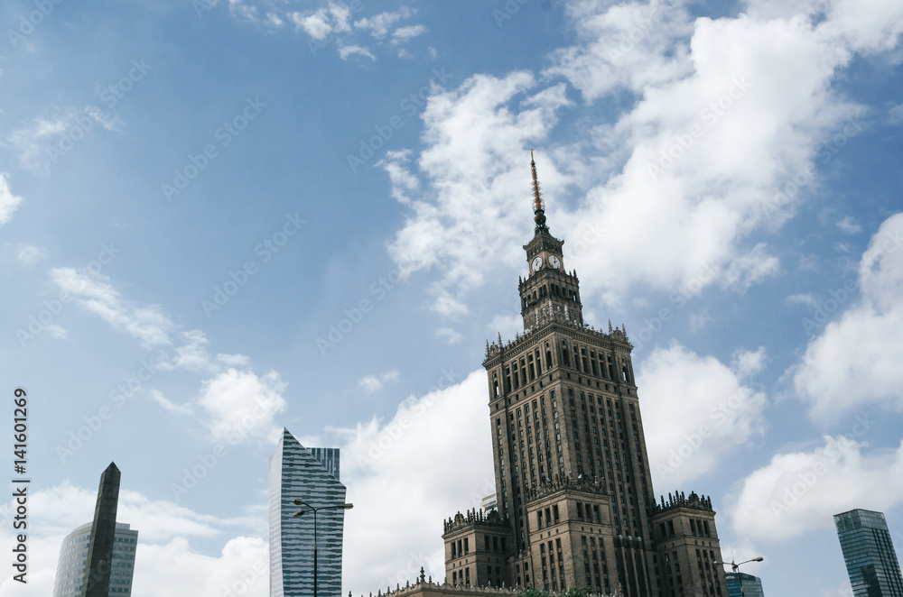 Warsaw skyline. Top of Palace of Culture and Science, skyscraper, symbol of communism and stalinism on blue sky, clouds background.