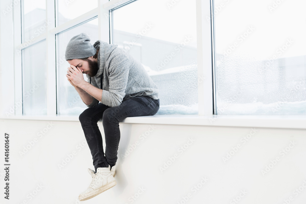 Sad young man with eyes closed on window sill Sad young man with eyes closed on window sill