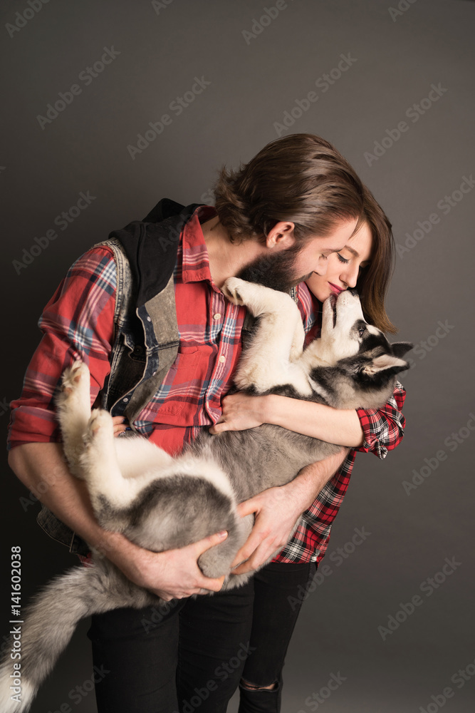 Young couple holding husky puppy Young couple holding husky puppy