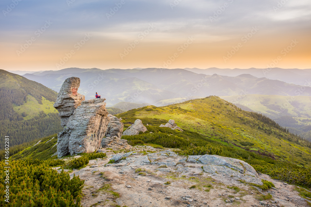 man meditates on a rock in the mountains.