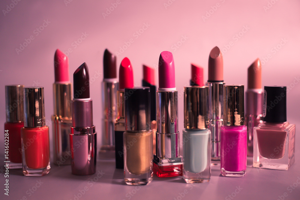 Set of multi-colored lipsticks and nail polishes on a pink background Set of multi-colored lipsticks and nail polishes on a pink background