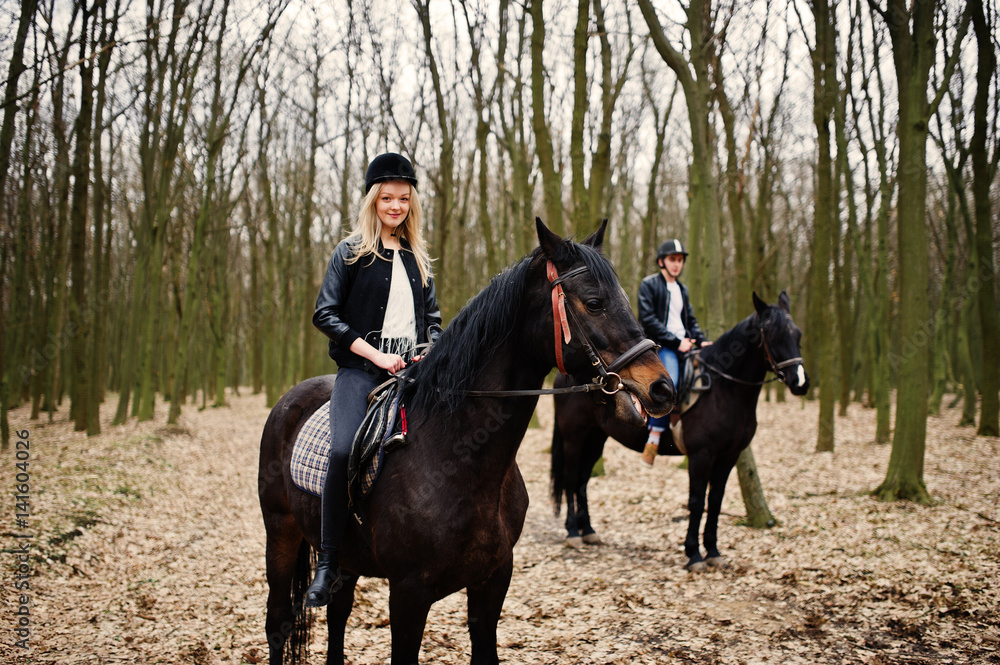 Young stylish couple riding on horses at autumn forest. Young stylish couple riding on horses at autumn forest.