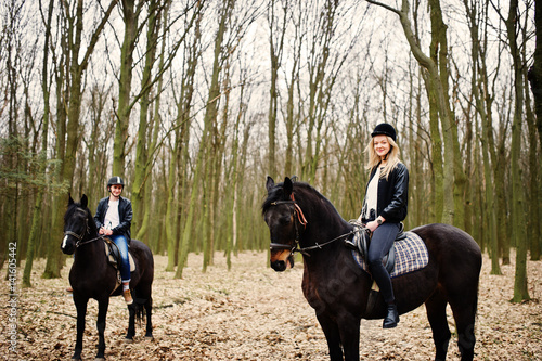 Young stylish couple riding on horses at autumn forest.