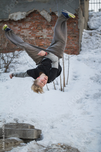 Backflip parkour in winter snow park - blonde hair teenager photo