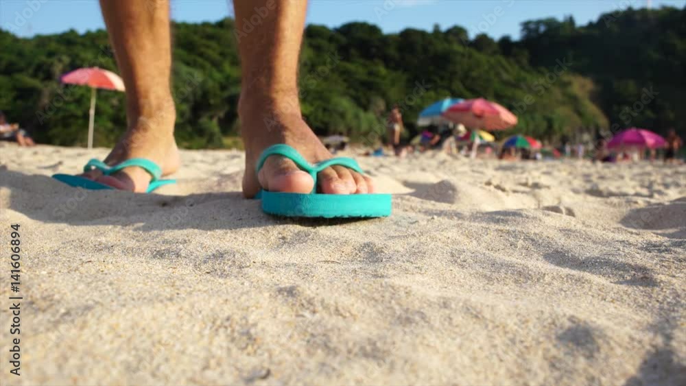 Close-up of flip-flops on sandy beach. Man on vacation. UHD Close-up of flip-flops on sandy beach. Man on vacation. UHD