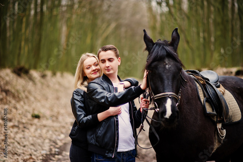 Young stylish couple in love near horse at autumn forest.