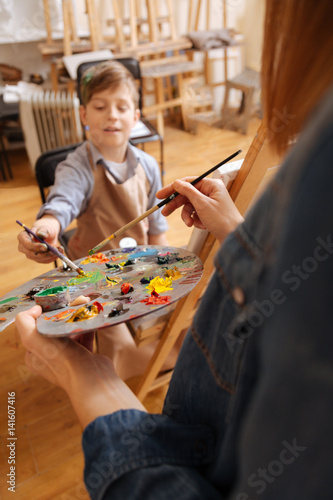 Helpful painter teaching art kid in the studio