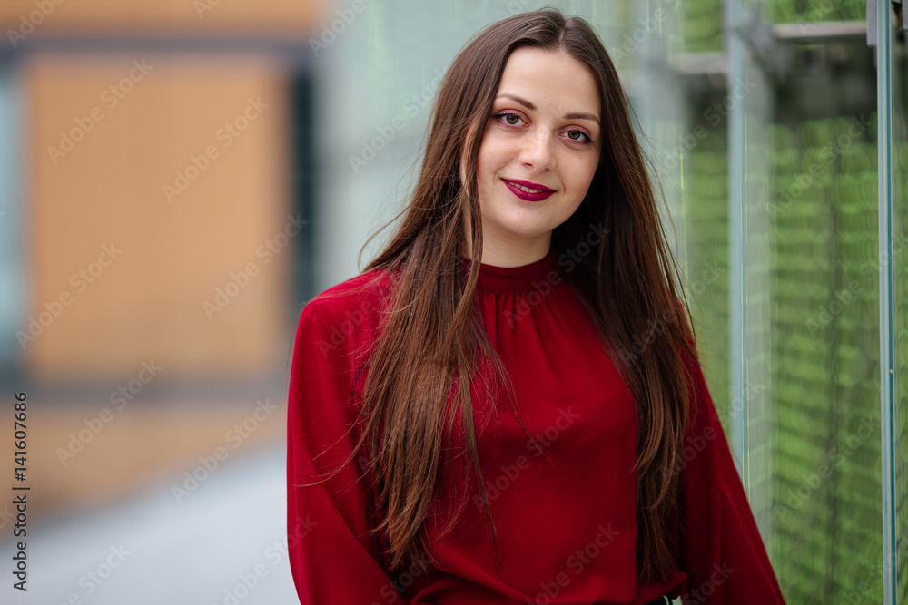 Young business woman standing near wall and smile to camera Young business woman standing near wall and smile to camera