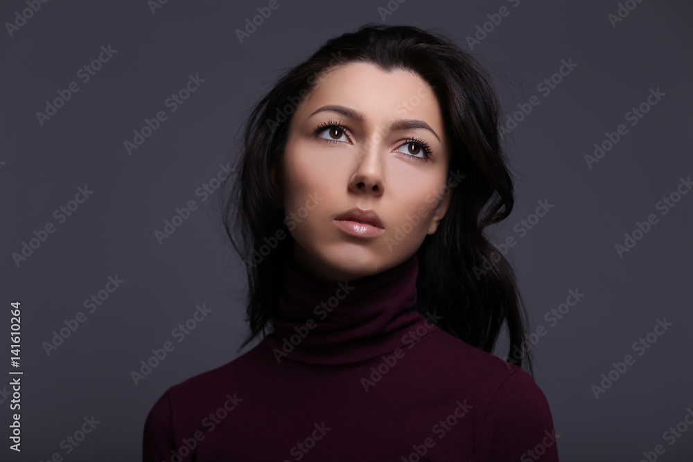 Beautiful sad thoughtful girl in a turtleneck on a gray background Beautiful sad thoughtful girl in a turtleneck on a gray background