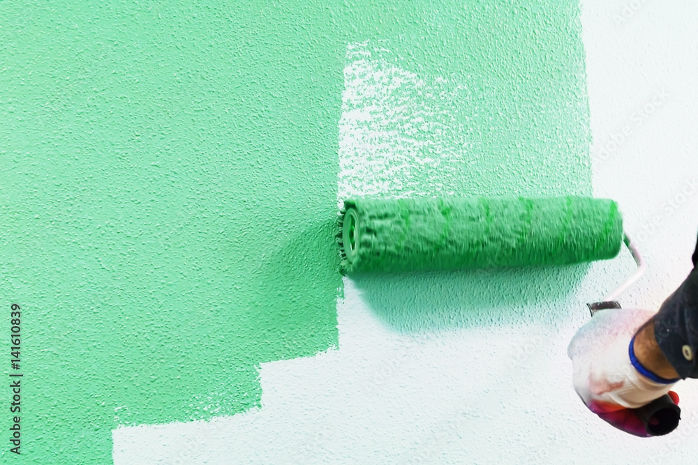 Obraz premium rasit hand wall paint using a paint roller while working indoors
