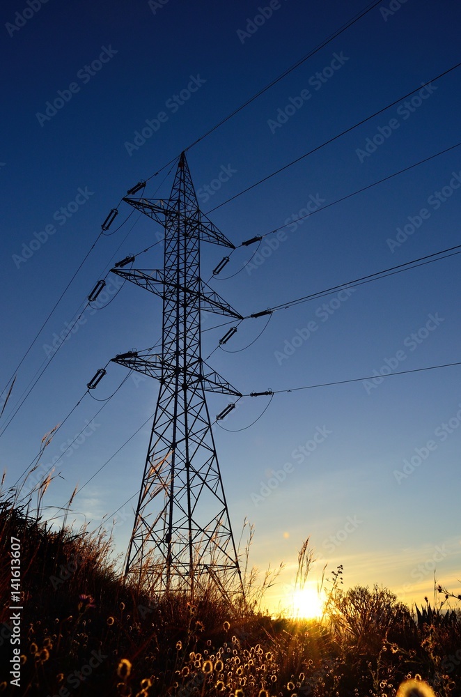 Fototapeta premium Electric tower backlit at sunrise, view from below