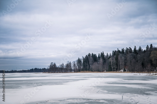 A peaceful winter landscape with a frozen lake in overcast day