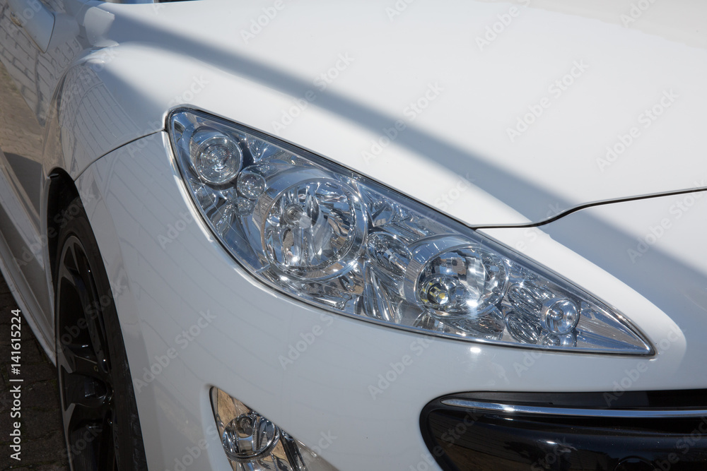 The front headlight of a white sports car
