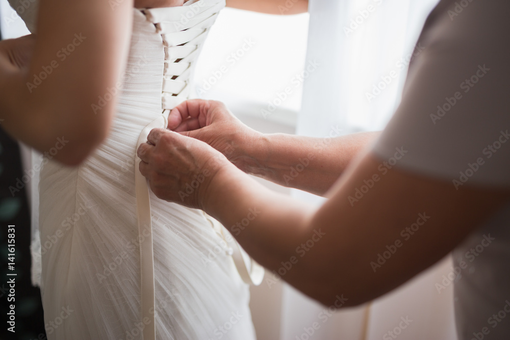 Mother helping to wear wedding dress