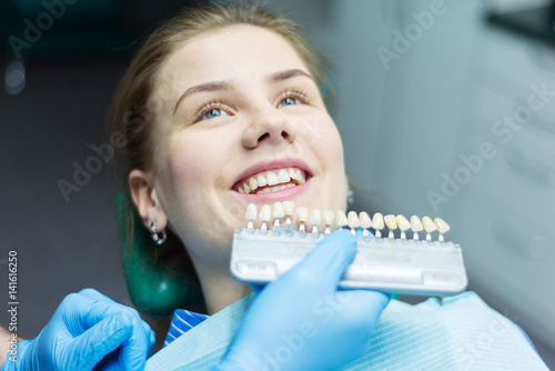 Close up portrait of Young women in dentist chair, Check and select the color of the teeth. Dentist makes the process of treatment in dental clinic office.Dentist