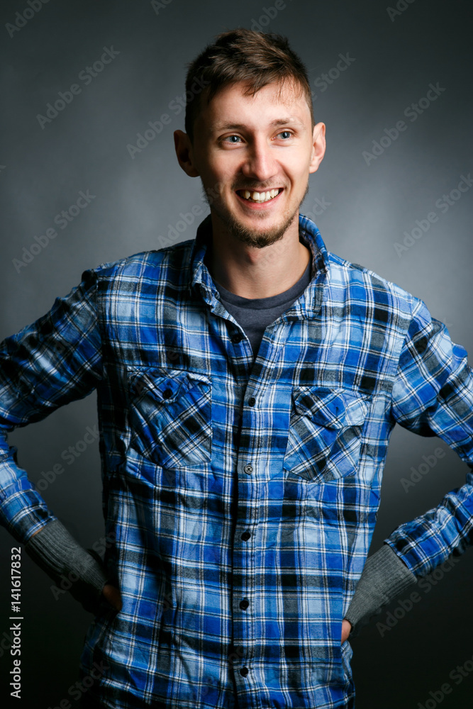Fototapeta premium Cheerful young man in plaid shirt smiles