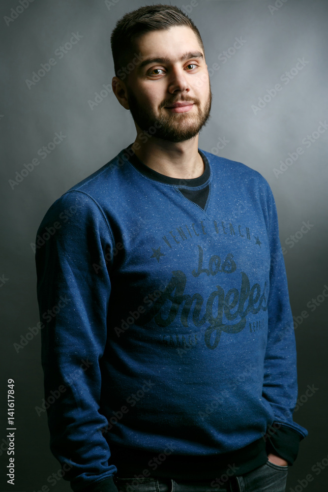 Handsome bearded man with broad shoulders poses in blue sweater