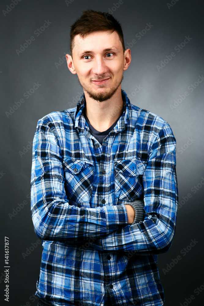 Handsome smiling man in blue plaid shirt crosses his hands on chest Handsome smiling man in blue plaid shirt crosses his hands on chest