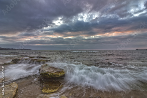  long exposure seascape with slow shutter and waves flowing out at sunset