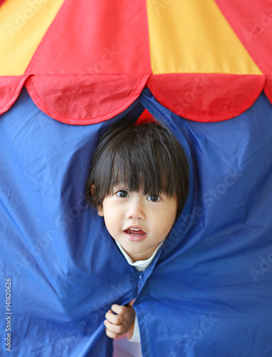 Cute little child girl playing hiding in a kid's tent