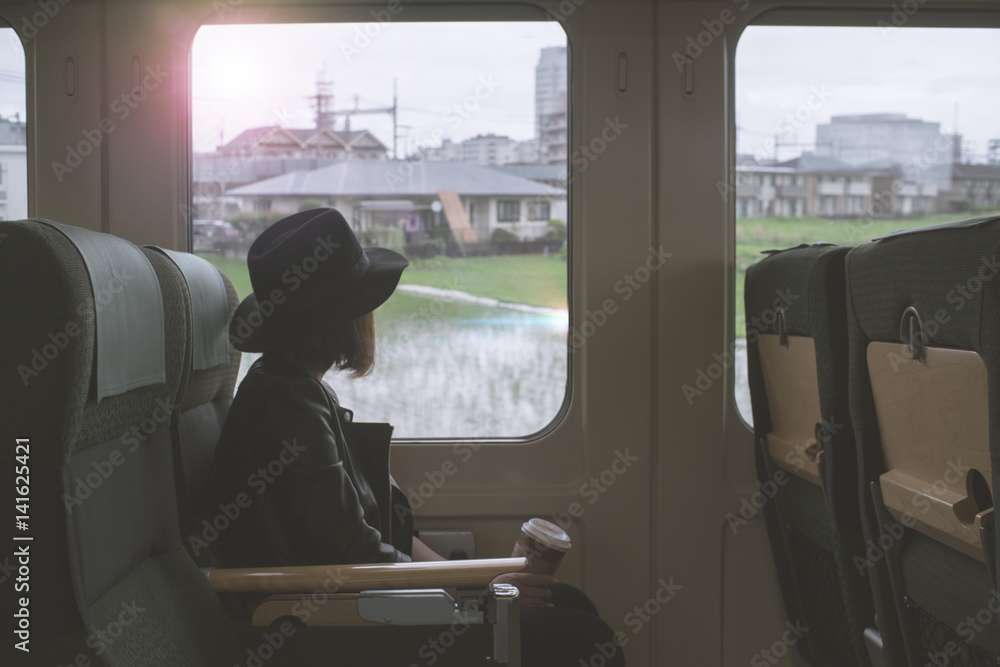 Enjoying travel. Young pretty woman traveling by the japan classic train from hakata to yufuin Japan (Limited Express Yufuin no Mori) sitting near the window. vintage filter. Enjoying travel. Young pretty woman traveling by the japan classic train from hakata to yufuin Japan (Limited Express Yufuin no Mori) sitting near the window. vintage filter.