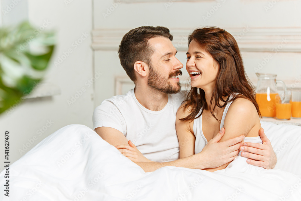 Young adult heterosexual couple lying on bed in bedroom Young adult heterosexual couple lying on bed in bedroom