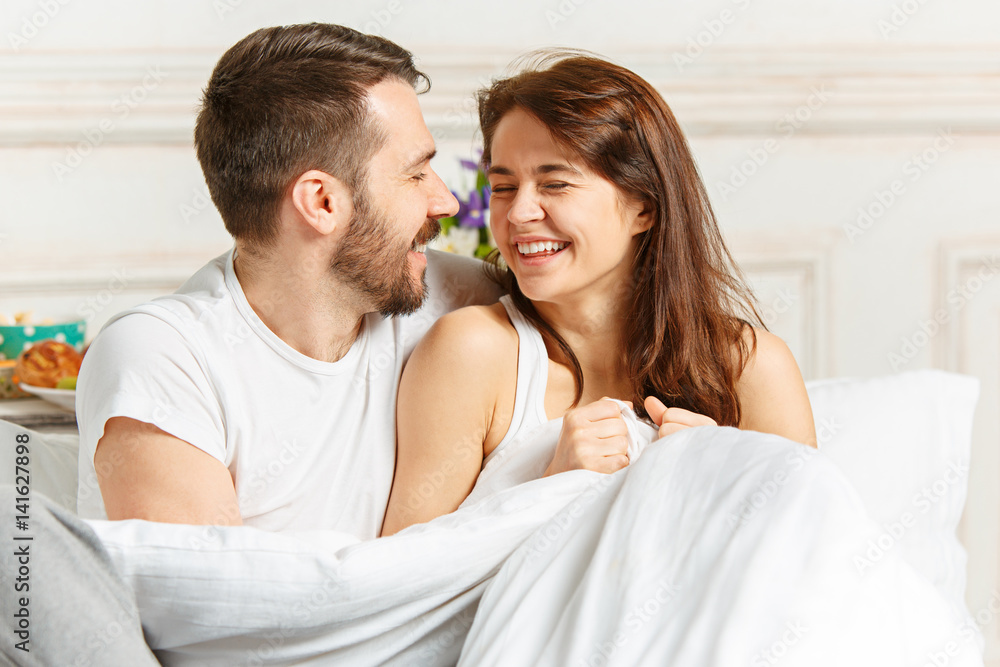 Young adult heterosexual couple lying on bed in bedroom Young adult heterosexual couple lying on bed in bedroom