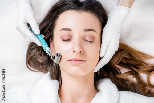 Making dry needlying procedure on woman's face in the cosmetology office photo