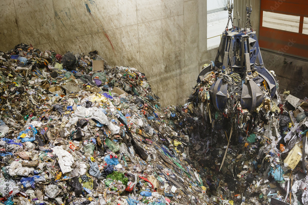 Mechanical claw hand grabbing pile of mixed waste