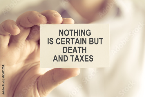 Businessman holding NOTHING IS CERTAIN BUT DEATH AND TAXES message card