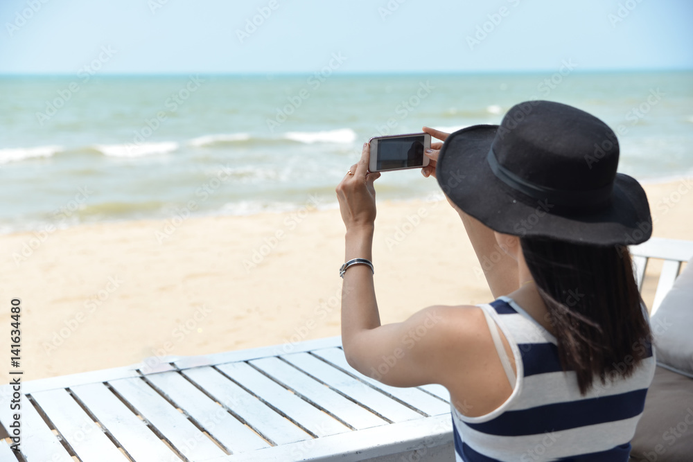 Beautiful woman holding smartphone,take photo,happy and smile,with sea and sky, Pataya inThailand.