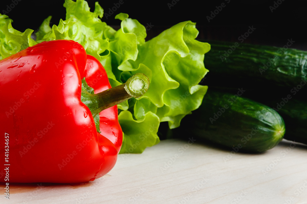 Fresh vegetables on the table: red pepper, lettuce, cucumber. Cutting board Fresh vegetables on the table: red pepper, lettuce, cucumber. Cutting board