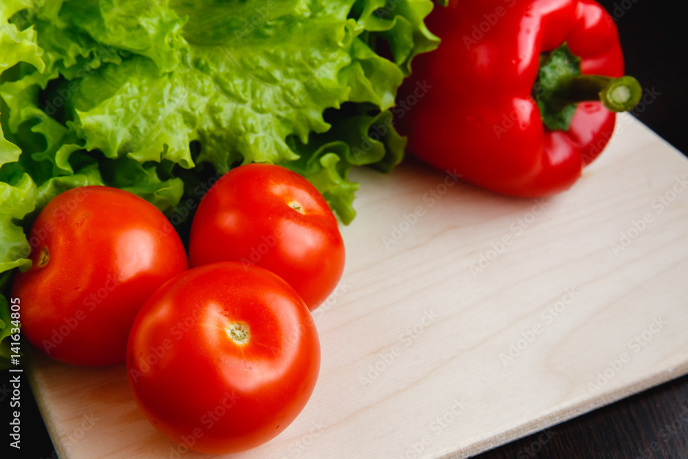 Fresh vegetables on the table: red pepper, lettuce, cucumber, tomatoes. Cutting board Fresh vegetables on the table: red pepper, lettuce, cucumber, tomatoes. Cutting board