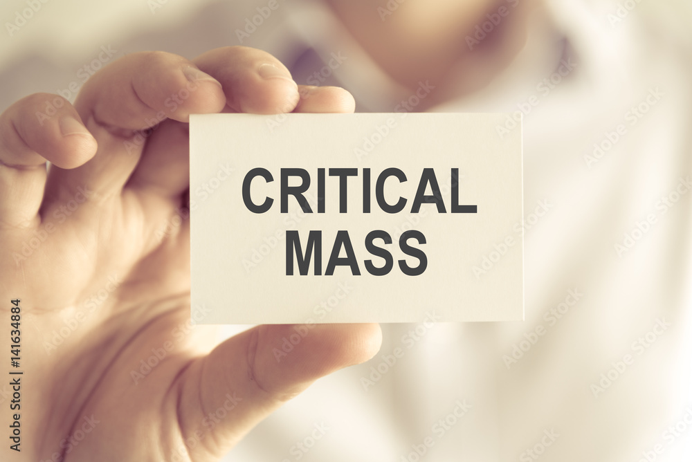 Businessman holding CRITICAL MASS message card Businessman holding CRITICAL MASS message card