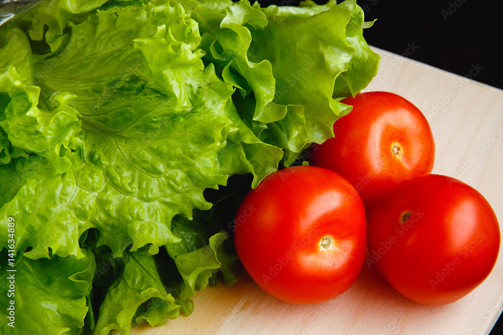 Fresh vegetables on the table: lettuce, tomatoes. Cutting board Fresh vegetables on the table: lettuce, tomatoes. Cutting board