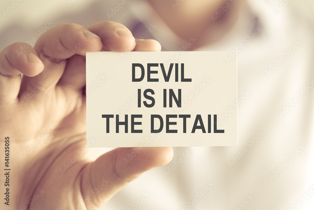 Businessman holding DEVIL IS IN THE DETAIL message card