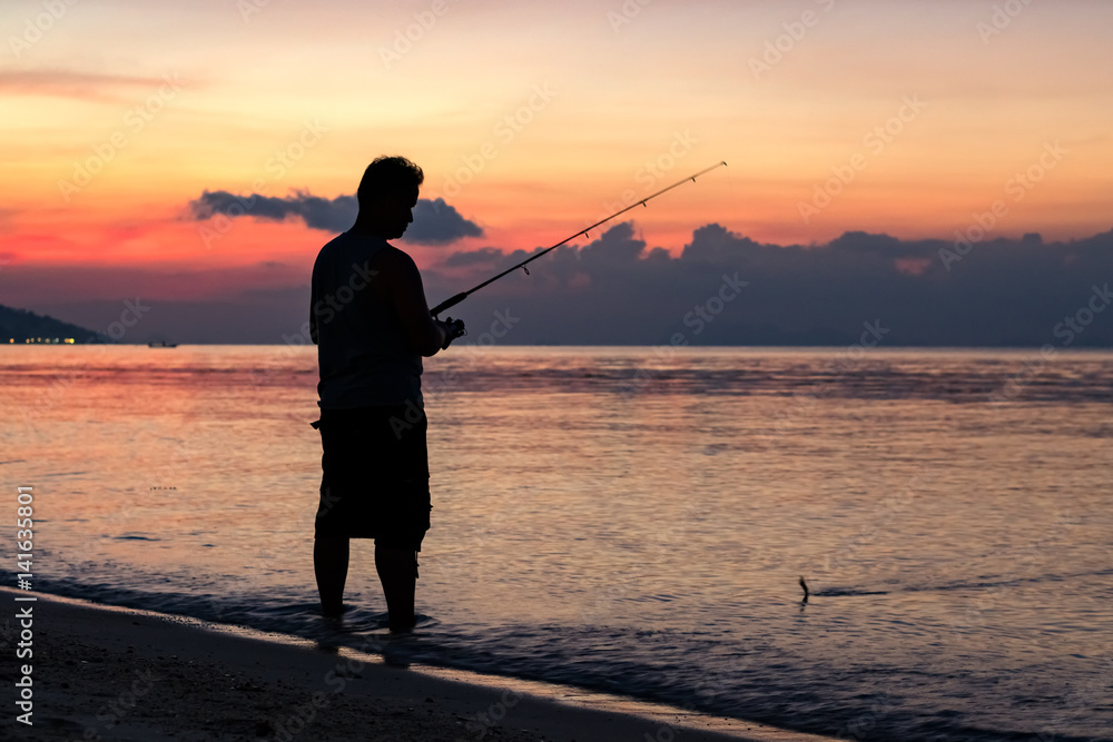 Fisherman on the beach against a tropical sunset background
