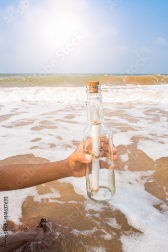 Bottle with a message in the hand on the beach.
