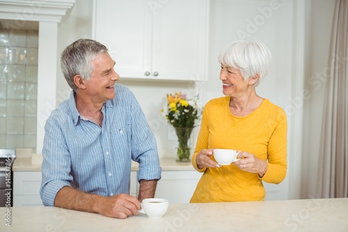Happy senior couple having coffee in kitchen 