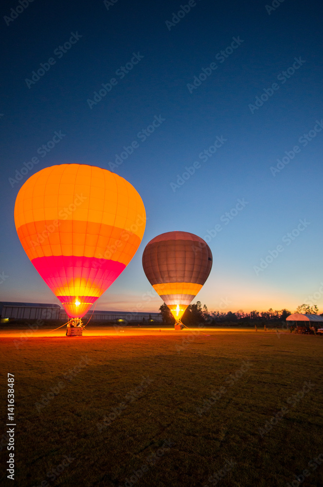 Obraz premium Two big balloon ready to take off at green field in twilight sky