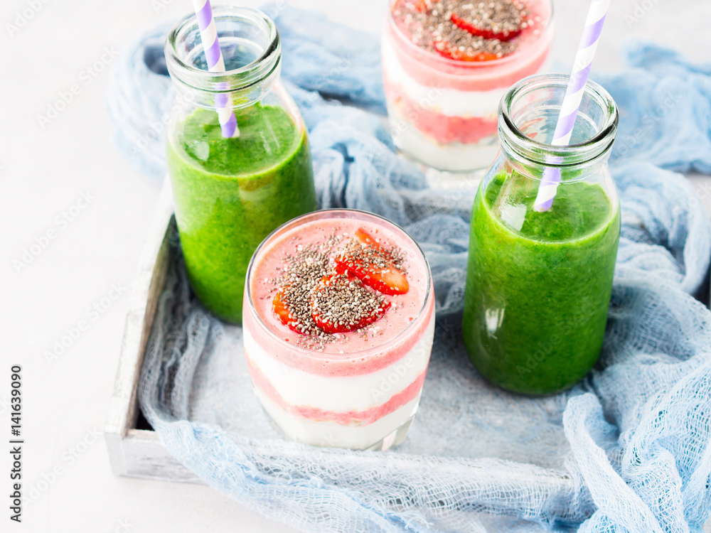 Healthy food concept green smoothie yogurt strawberries chia seeds breakfast on white gray tray blue textile. Fruit Vegetable juice glass bottle Healthy food concept green smoothie yogurt strawberries chia seeds breakfast on white gray tray blue textile. Fruit Vegetable juice glass bottle
