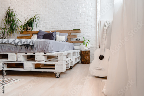 White interior with pallets, bed and guitar