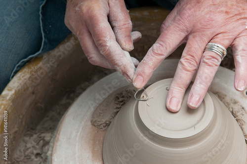 Pottery making with womans hands working at the pottery wheel