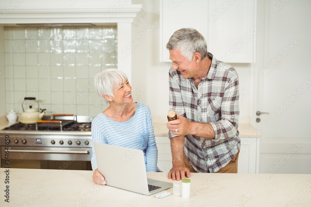Senior couple holding medicine bottle and using laptop Senior couple holding medicine bottle and using laptop