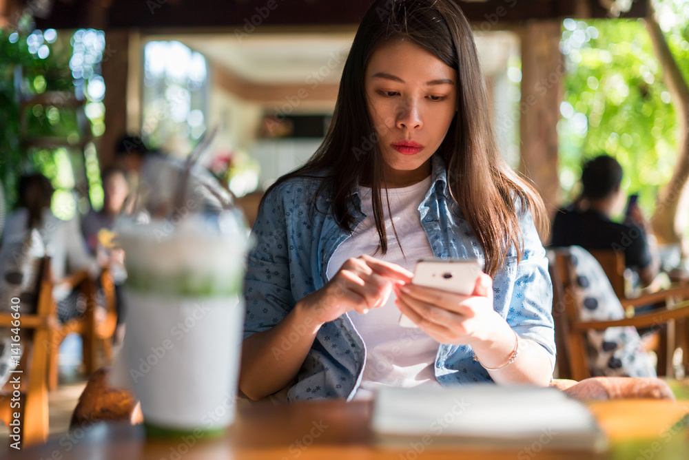 Young asian woman using smartphone in coffee shop.