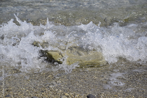 Sea waves run ashore, bubbling and stone covering