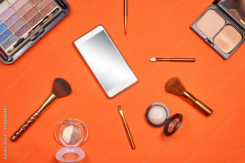 Flat lay, top view feminine table desk isolated on white. Workspace with cosmetics, phone, glasses, lipstick, nail lacquer, watches, mascara and eyeshadow in gold. Golden and black tones. Flat lay, top view feminine table desk isolated on white. Workspace with cosmetics, phone, glasses, lipstick, nail lacquer, watches, mascara and eyeshadow in gold. Golden and black tones.