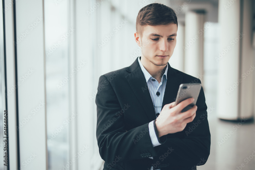 View of a young attractive business man using smartphone in office View of a young attractive business man using smartphone in office