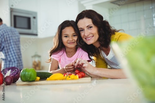 Mother and daughter preparing salad in kitchen