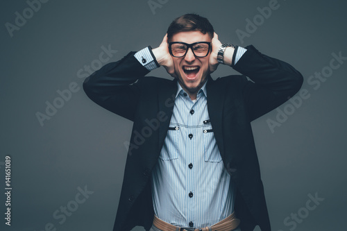 Tablou pe pânză Portrait of a serious young man covering both ears with hands